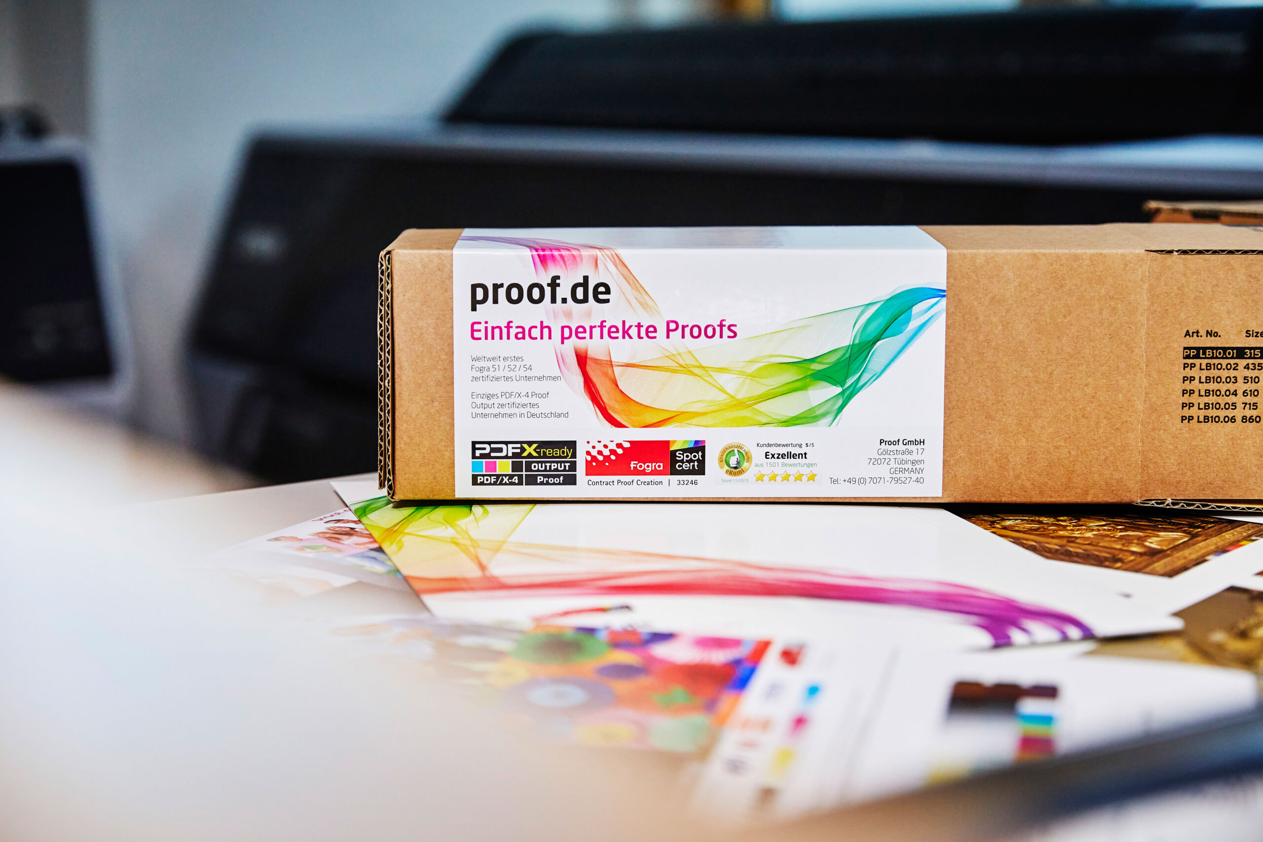 Proof.de : un tube d'expédition de la Proof GmbH est prêt à être envoyé, au premier plan les formes de test de la Proof GmbH pour Fogra 39, Fogra47, Fogra51 et Fogra52.